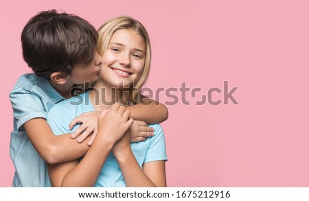 Little brother kissing sister on cheek 