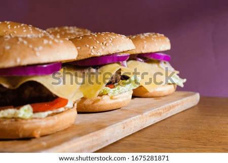Homemade cheeseburgers on a wooden tray.