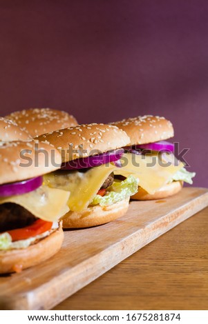 Homemade cheeseburgers on a wooden tray.