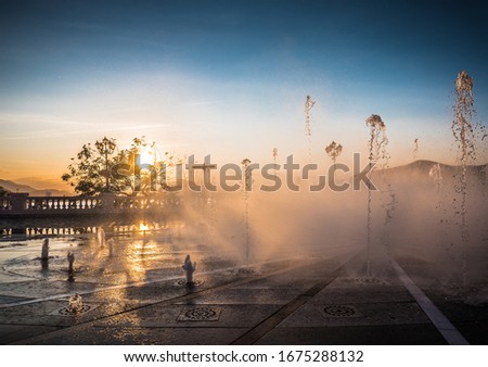Outdoor fountain on sunset time. Splash of water with sun rays. Beautiful nature