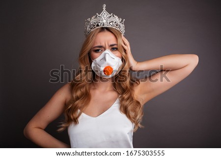 Coronavirus concept. Woman is wearing mask and crown on a gray background. Outbreak of the corona virus in China, illness.