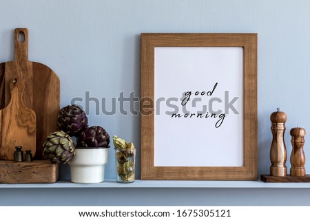 Modern composition on the kitchen interior with mock up photo frame, wooden cutting board, herbs, vegetables and  kitchen accessories in stylish home decor.