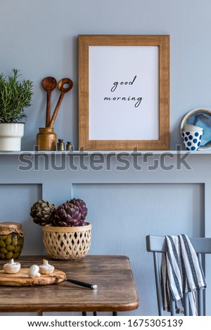 Stylish composition of kitchen interior with wooden family table, vegetables, herbs, food supplies, mock up photo frame and kitchen accessories in gray concept of home decor. 