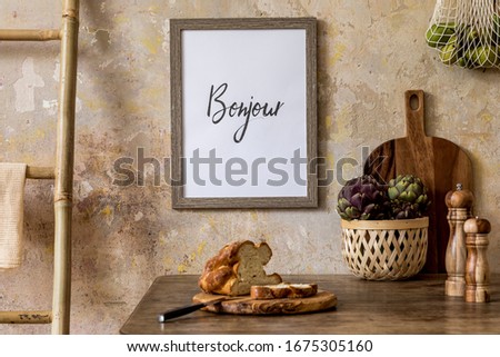 Stylish composition of kitchen interior with wooden mock up frame, family table, ladder, vegetables, dessert and kitchen accessories in wabi sabi concept of home decor. 