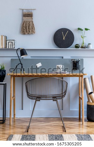 Scandinavian interior design of open space with wooden desk, modern chair, wood paneling with shelf, plant, carpet, office supplies and elegant personal accessories in home decor.