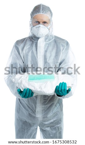 a man in a white suit, mask and glasses, holds a protective kit, the doctor looks at us and offers to wear styly clothes. virologist specialist. individual protection of a person. isolated Royalty-Free Stock Photo #1675308532