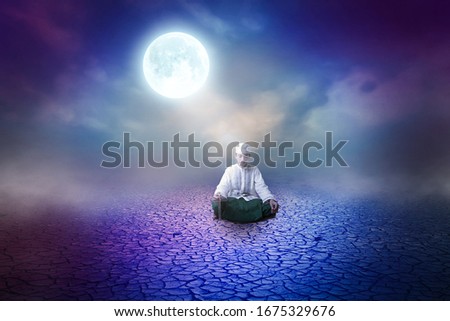 Young man Asian moslem pray on the wooden floor with night sky full moon background 