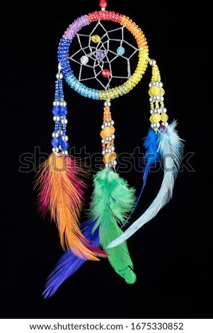 Pearl-embroidered dream catcher with colorful feathers and pearls against a black background