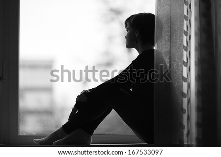 sad girl on the windowsill looking out the window Royalty-Free Stock Photo #167533097