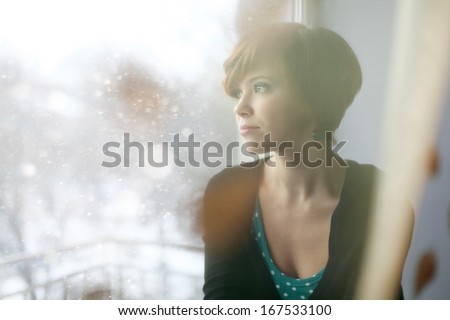 sad girl on the windowsill looking out the window Royalty-Free Stock Photo #167533100