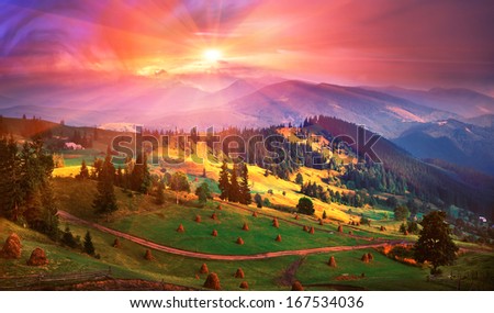  By late summer, mountaineers clean grass in haystack Beautiful view of the mountains and cabin haystacks on the background of bright colors of the sky and sunset-joy for the traveler