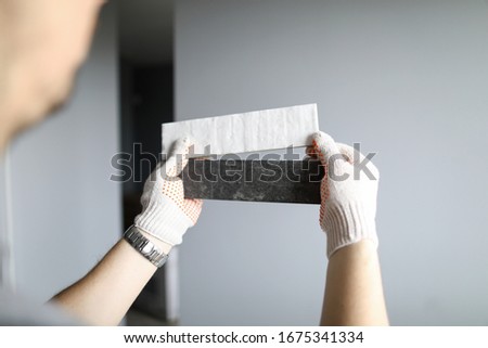 Repairman in gloves choosing right color of materials for interior details over grey walls background. Professional repairman during work concept