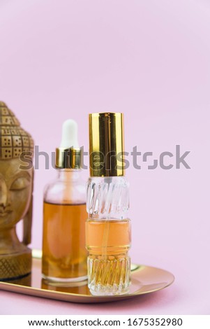 Spa treatment bottle of natural organic oil essence serum collagen. Aromatherapy and beauty concept. Aroma bottle with essential oils and Buddha on pink background. Copy space for text. 