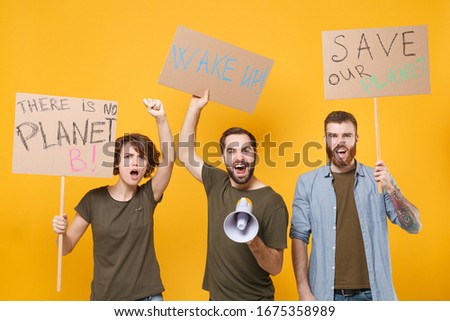 Protesting three people hold protest signs broadsheet placard scream in megaphone clenching fist isolated on yellow background. Stop nature garbage ecology environment protection concept. Save planet