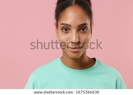 Close up of smiling young african american woman girl in green sweatshirt posing isolated on pastel pink wall background studio portrait. People lifestyle concept. Mock up copy space. Looking camera