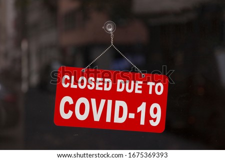 Close-up on a red closed sign in the window of a shop displaying the message "Closed due to Covid-19". Royalty-Free Stock Photo #1675369393
