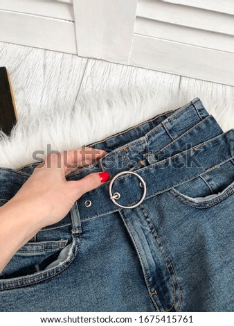 Denim belt on blue jeans close-up on a wooden background