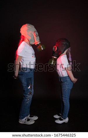 Two girls posing in respirators on black background