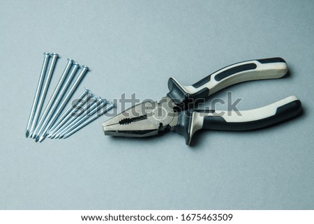 
old pliers on a gray background with nails,old pliers on a gray background