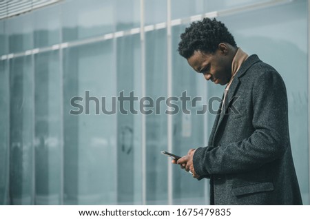 businessman standing in front of office building with his smartphone