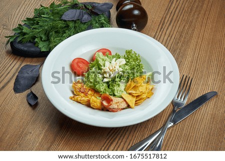 Caesar salad with croutons, parmesan, bacon, chicken, egg in whte bowl on white background. Restaurant serving. Close up with copy space.