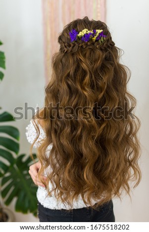 A young girl with a beautiful hairstyle long hair stands with the back