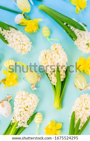Easter scene with spring flowers and colored eggs, flat lay on blue background, toned