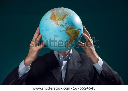 A man in suit holding globe in front of his face. Business, education and idea concept