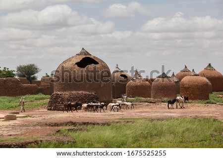 Farmer in Sahel zone western Africa countryside idyllic landscape with traditional  African mud huts Royalty-Free Stock Photo #1675525255