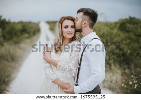 Smiling bride and groom spending time together. Posing on the mountain hills background. Dressed in white dress beautiful blonde caucasian bride and handsome groom.  