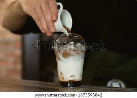 barista mixes coffee with milk and ice