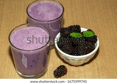 blackberry fruit smoothie and green mint isolated on brown background. Healthy and yummy drink