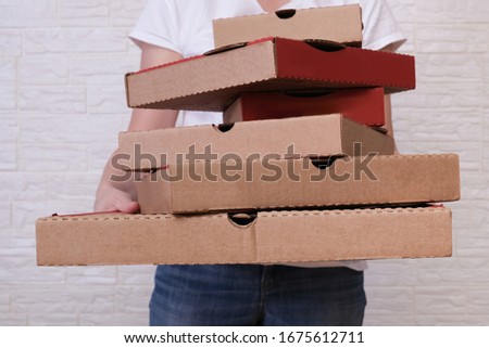 Woman holding many stacked in disorder carton pizza boxes of different sizes, restaurant delivery concept.