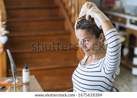 Home made hair dye at home for beauty young caucasian woman looking at the mirror - stay at home concept for coronavirus emergency worldwide pandemic contagion Royalty-Free Stock Photo #1675618384