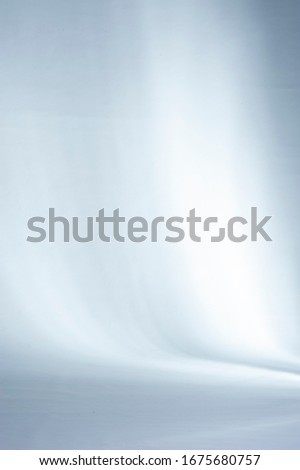 Shadows and beams of lights on a white studio backdrop.