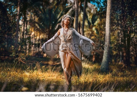 beautiful young stylish woman in turban walking on the field
