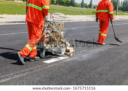 Road workers use hot-melt scribing machines to painting dividing line on asphalt road surface in the city. Royalty-Free Stock Photo #1675715116