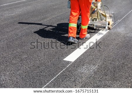 Road workers use hot-melt scribing machines to painting dividing line on asphalt road surface in the city. Royalty-Free Stock Photo #1675715131