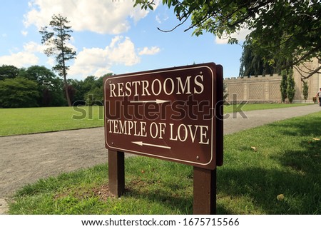 Sign with arrows pointing in two different directions. Sign says, RESTROOMS and also TEMPLE OF LOVE.                                