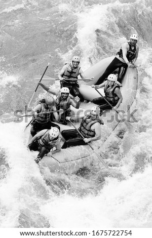 A group of people in a white water raft, guided by a woman rowing through rapids on a river in the summer, showcasing teamwork and action.
