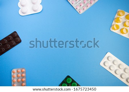 Set of pills in white foil blisters capsule tablet packaging lay flat and isolated on blue background. For pharmaceutical, medical and science theme.