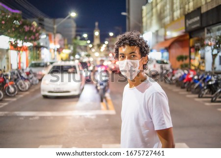 22 year old man with white protective mask on the street at night crosses the safety lane