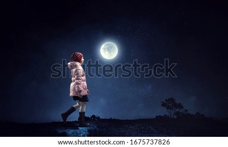 A little girl walks on a beautiful full moon night.
