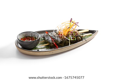 Spicy mutton with grape leaves. Delicious meat with cut vegetables and sauce. Tasty restaurant dish on tray. Exquisite food composition. Traditional western cuisine. Meal presentation