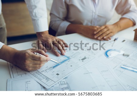 The partnership engineering man or co-workers working on a project and discussing together with looking at blueprint paperwork.