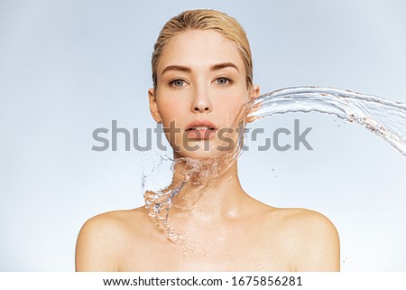 Photo of  young woman with clean skin and splash of water. Portrait of blonde woman with drops of water around her face. Spa treatment. Girl washing her body with water. Water and body. Royalty-Free Stock Photo #1675856281