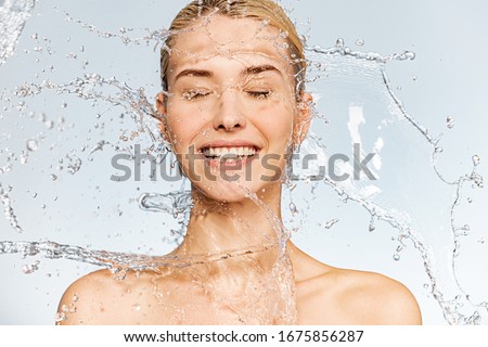 Photo of  young  woman with clean skin and splash of water. Portrait of smiling woman with drops of water around her face. Spa treatment. Happy girl washing her body with water. Water and body. Royalty-Free Stock Photo #1675856287