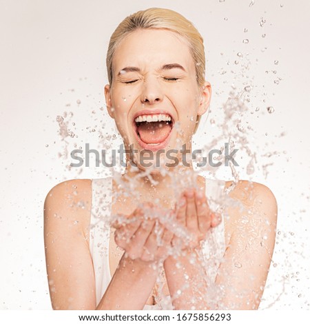 Photo of  screaming woman with falling water into her palms. Young woman with clean skin and splash of water near face.  Spa treatment. Girl washing her body with water.  Skin and body care.  