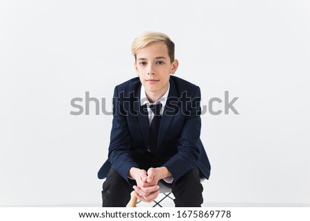 Portrait of stylish school boy teenager in white shirt and jacket against white background.