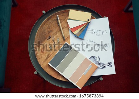 High angle view of design sketches and colored patterns lying on wooden table